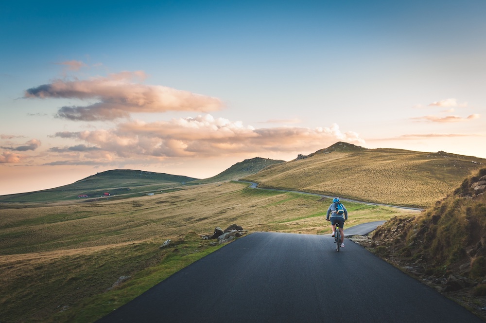 Biker on road next to green fields